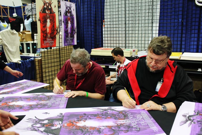 Jock (L) and Guillermo Del Toro (R) signing Jock's poster for Del Toro's film 'Pan's Labyrinth' at the Mondo booth at San Diego Comic Con 2014